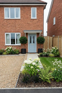 Showcase · House front with bay standards either side of the door and a green-and-white border by the gravel drive